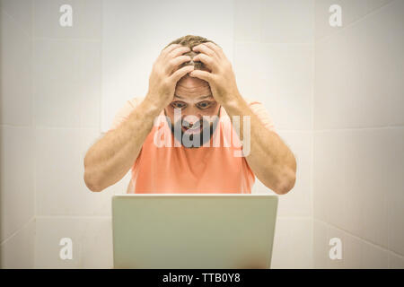 Businessman travaille avec un ordinateur portable tout en étant assis sur les toilettes Banque D'Images