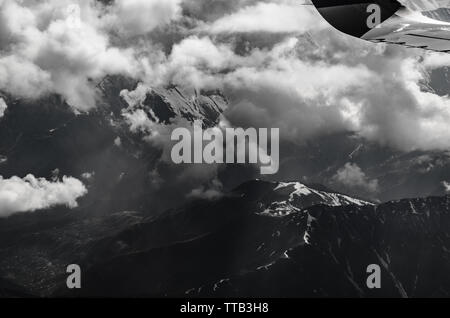 Photographie en noir et blanc d'des envoûtantes montagnes de l'himalaya culminant à travers les nuages sur un jour nuageux du vol de Delhi à Srinagar. Banque D'Images