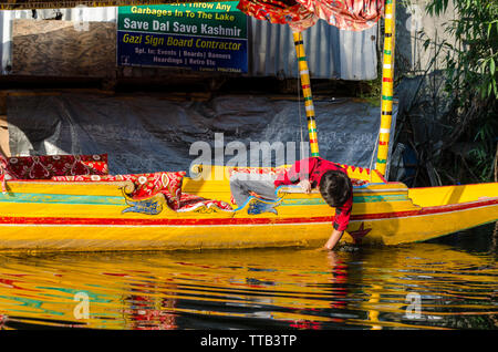 Garçon plonge sa main dans l'eau devant un conseil d'inciter les gens à ne pas jeter leurs ordures dans Dal Lake, à Srinagar, Jammu-et-Cachemire, l'Inde Banque D'Images