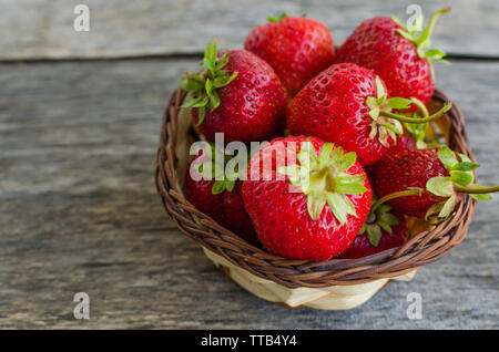 Une fraise mûre dans panier en osier sur la vieille table en bois Banque D'Images