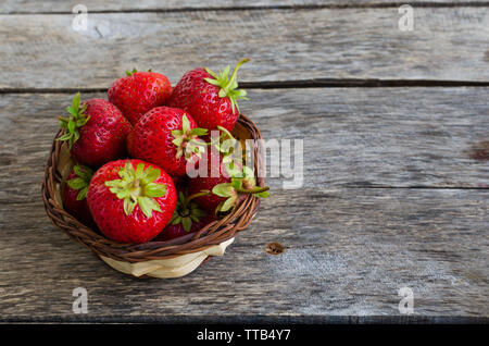 Une fraise mûre dans panier en osier sur la vieille table en bois Banque D'Images