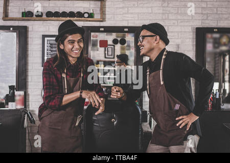 Portrait de deux professionnels styliste coiffure coiffure avec tablier, debout à un barbier. Hairstylist et client au salon concept Banque D'Images