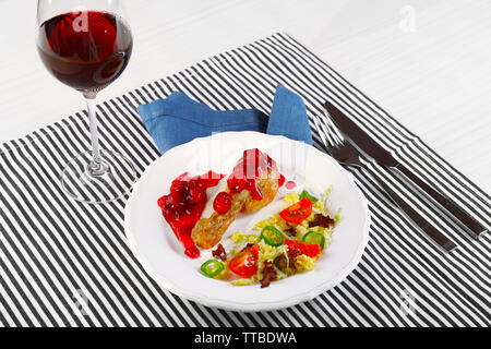 Plat de poulet au four salade de légumes et de jambe en plaque blanche avec verre de vin sur la table avec des nappes, gros plan Banque D'Images