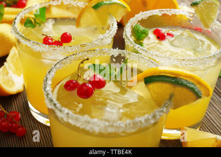 Verres de jus de citron avec groseilles rouges sur la table en bois, gros plan Banque D'Images