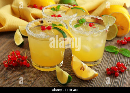 Verres de jus de citron avec groseilles rouges sur la table en bois, gros plan Banque D'Images