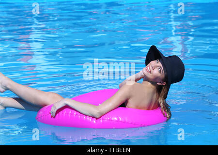 Jeune femme se reposant sur rose bague en caoutchouc dans la piscine Banque D'Images