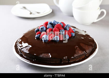 Délicieux gâteau au chocolat avec des fruits d'été sur nappe gris background Banque D'Images