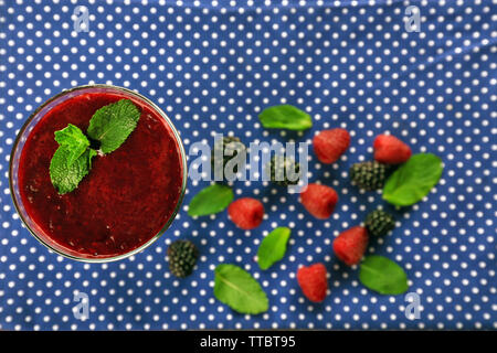 Verre de cocktail de fruits frais et de baies bleu foncé sur fond de tissu à pois Banque D'Images