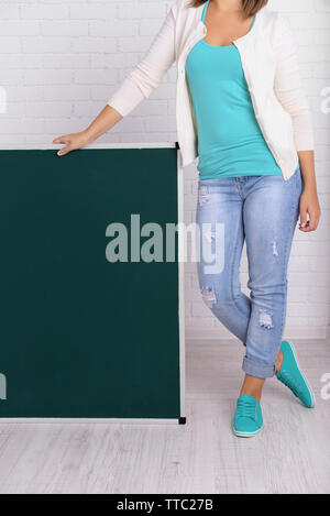 Femme en relation causale avec tableau noir vert contre le mur de briques, Close up Banque D'Images