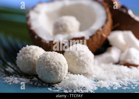 Bonbons dans flocons de noix de coco et de noix de coco fraîche sur la couleur de fond de bois Banque D'Images