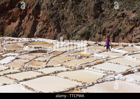 Un homme qui marche le long de l'étangs à Salineras de Maras, Pérou. Banque D'Images