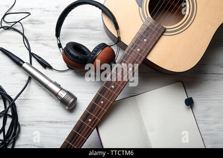 Guitare acoustique, écouteurs, microphone et l'ordinateur portable ouvert sur fond de bois, Close up Banque D'Images