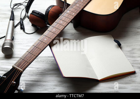 Guitare acoustique, écouteurs, microphone et l'ordinateur portable ouvert sur fond de bois, Close up Banque D'Images