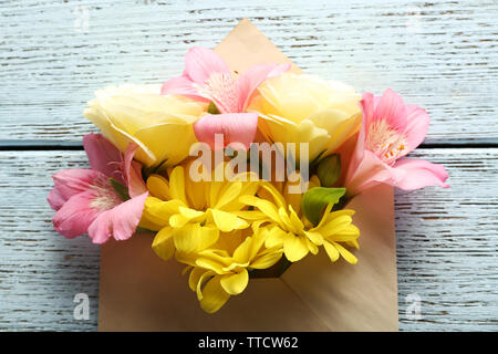Bouquet de fleurs fraîches dans une enveloppe sur fond de bois Banque D'Images