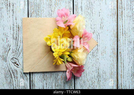 Bouquet de fleurs fraîches dans une enveloppe sur fond de bois Banque D'Images