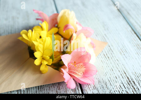 Bouquet de fleurs fraîches dans une enveloppe sur fond de bois Banque D'Images