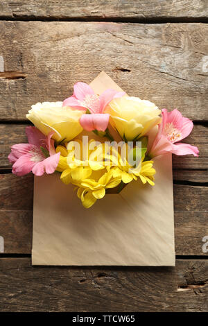 Bouquet de fleurs fraîches dans une enveloppe sur fond de bois Banque D'Images