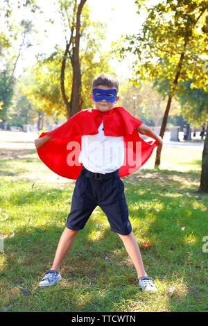 Garçon habillé en super-héros avec des gants de boxe joue au parc Banque D'Images