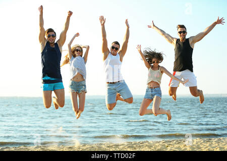 Happy friends jumping à la plage, à l'extérieur Banque D'Images