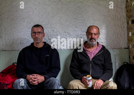 Deux hommes sans-abri, l'un de l'Irlande (verres) et l'autre de l'Espagne (la barbe) assis sur un banc dans Rusking Park, Londres. Banque D'Images