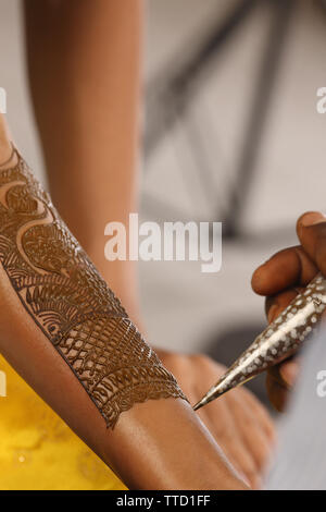 Main d'artiste appliquant mehendi sur une main de mariée Banque D'Images