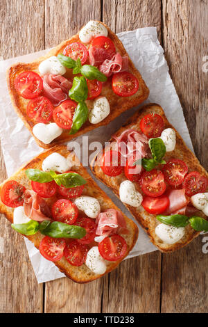 Italian open sandwiches avec de la mozzarella, tomates, jambon et basilic gros plan sur la table. Haut Vertical Vue de dessus Banque D'Images