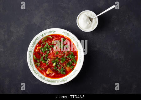 Traditionnel russe ukrainien traditionnel soupe rouge betterave bortsch - avec de la crème sur fond noir en noir. Vue d'en haut. Banque D'Images