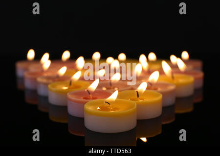 De nombreuses petites bougies brûlantes sur fond sombre Banque D'Images