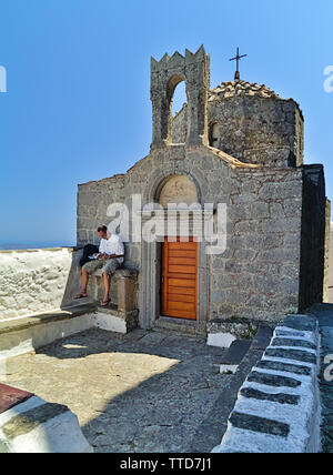 L'île de Patmos, Grèce, l'homme lit un livre en face de chapelle de Saint Jean l'Évangéliste monastère. Banque D'Images