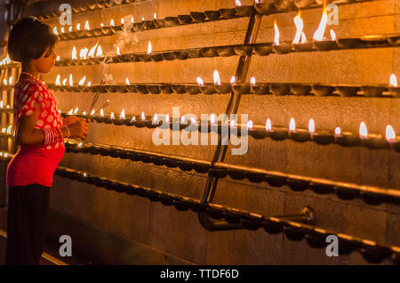 Une jeune fille s'allume une bougie dans un temple de Kataragama, Sri Lanka Banque D'Images