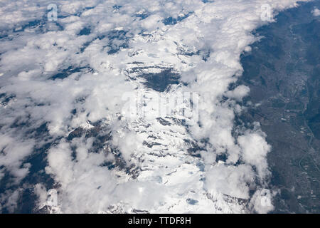 Vue sur une montagne à partir d'une fenêtre de la cabine d'un Boeing 737 volant au-dessus des nuages Banque D'Images