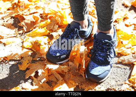 Les jambes de la femme dans des chaussures de course sur un fond de feuilles tombées Banque D'Images