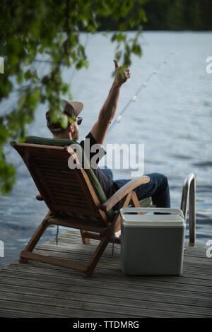 Homme mature de pêche jetée en bois près de cottage sur le lac en Finlande à l'été Banque D'Images