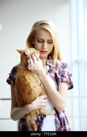 Jeune femme posant avec chat rouge dans les mains, Close up Banque D'Images