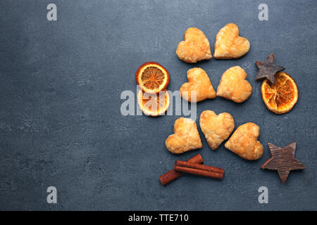 Des biscuits en forme de coeur avec des épices séchées sur fond gris foncé Banque D'Images