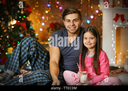 Frère aîné avec petite soeur assis dans un salon de Noël Banque D'Images