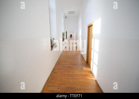 Long couloir vide à l'intérieur d'un vieux bâtiment avec murs fraîchement peints blancs et de parquet