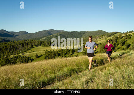 Un couple millénaire trail running ensemble au début de la lumière du matin. Une partie de leur propre, actif, mettre en place, et d'un style de vie sain. Le Montana, USA. Banque D'Images