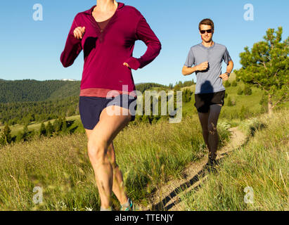 Un couple millénaire trail running ensemble au début de la lumière du matin. Une partie de leur propre, actif, mettre en place, et d'un style de vie sain. Le Montana, USA. Banque D'Images