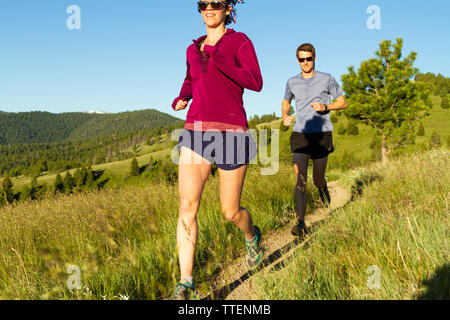 Un couple millénaire trail running ensemble au début de la lumière du matin. Une partie de leur propre, actif, mettre en place, et d'un style de vie sain. Le Montana, USA. Banque D'Images