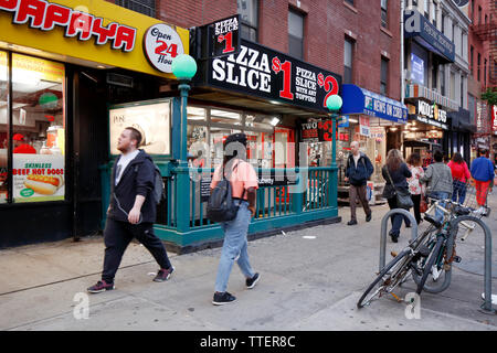 Les gens passent devant les restaurants à service rapide le long de la 23e Rue Ouest et la 6e Avenue à Manhattan, New York, NY. Banque D'Images