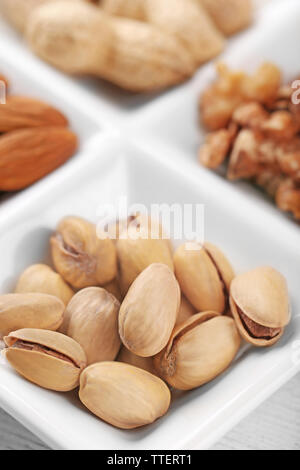 Les cerneaux de noix, amandes, pistaches, cacahuètes dans le rectangle en céramique plaque, close-up Banque D'Images