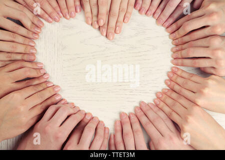 Beaucoup de les doigts en forme de coeur sur fond de bois Banque D'Images