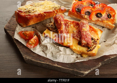 Pizza chaude baguettes avec bacon, jambon et salami sur table en bois Banque D'Images