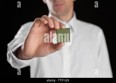 Man holding microprocesseur dans sa main sur fond noir Banque D'Images