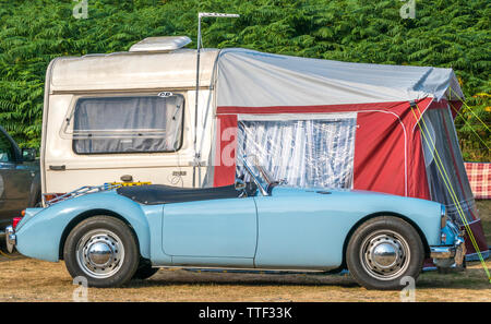 MGA Classique, Soft top, voiture de sport britannique dans la peinture bleu pâle, garé en face d'une Caravane avec auvent, sur un camping en Angleterre, Royaume-Uni. Banque D'Images