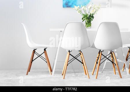 Salle à manger moderne. Chaises blanches et table avec bouquet de fleurs, abstract photo sur le mur Banque D'Images