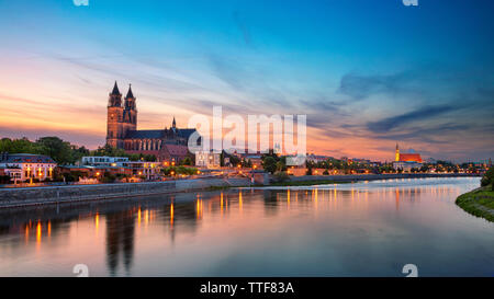 Magdeburg, Allemagne. Paysage urbain panoramique droit de Magdebourg, en Allemagne avec la réflexion de la ville sur le fleuve Elbe, au coucher du soleil. Banque D'Images