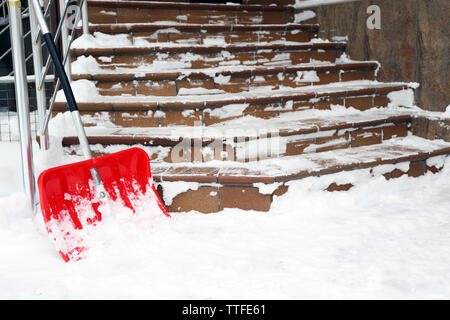 Pelle rouge pour l'enlèvement de la neige à côté d'escaliers Banque D'Images