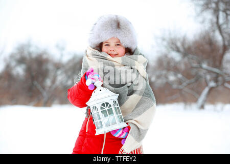 Petite fille avec des vêtements d'hiver holding white lanterne en plein air du parc de neige Banque D'Images